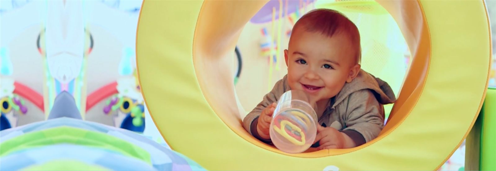 Bebé sonriendo mientras juega en un túnel de psicomotricidad de la escuela