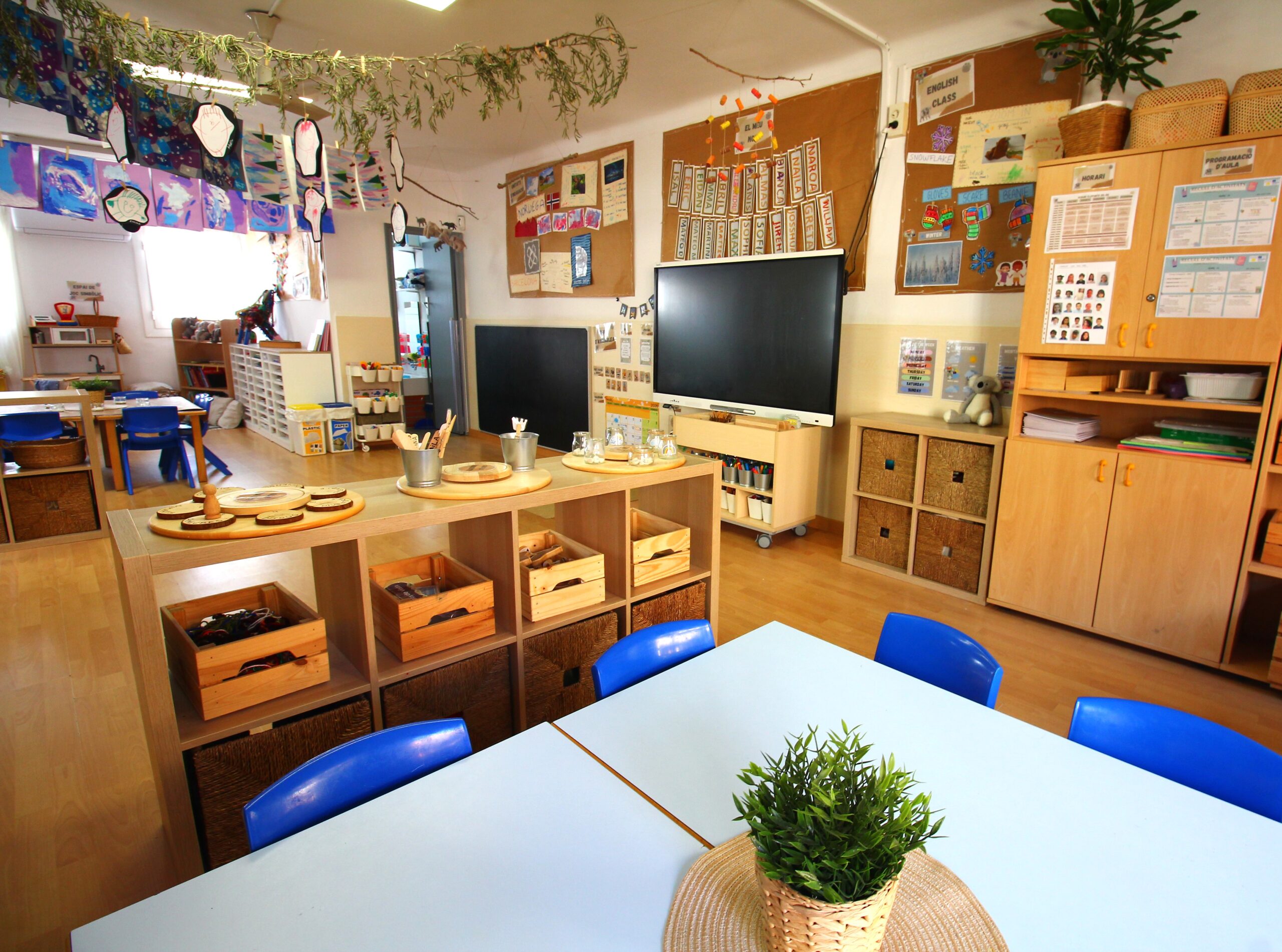 Aula de segon cicle amb taules i prestatgeries de fusta